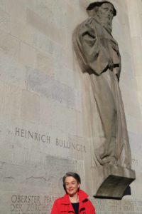 Die Autorin Barbara Hutzl-Ronge vor dem Grossmünster mit der Statue von Heinrich Bullinger